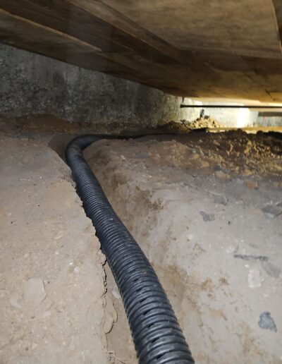 French drain being installed in a crawlspace or basement to manage water intrusion