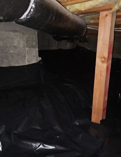interior of a crawl space with a black vapor barrier installed over the soil for managing moisture