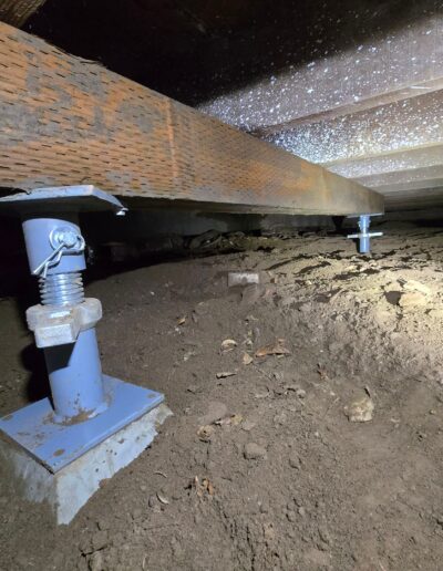 adjustable crawl space support jack system installed under a house's floor joists and beams to provide structural stability and lift sagging floors.